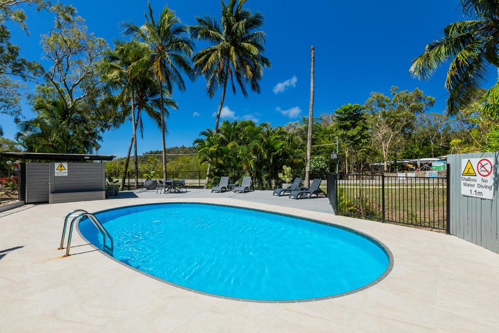 a swimming pool in a yard with palm trees at Kipara Tropical Rainforest Retreat in Airlie Beach