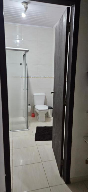 baño con aseo y puerta de cristal en Casa Vila da gloria, en São Francisco do Sul