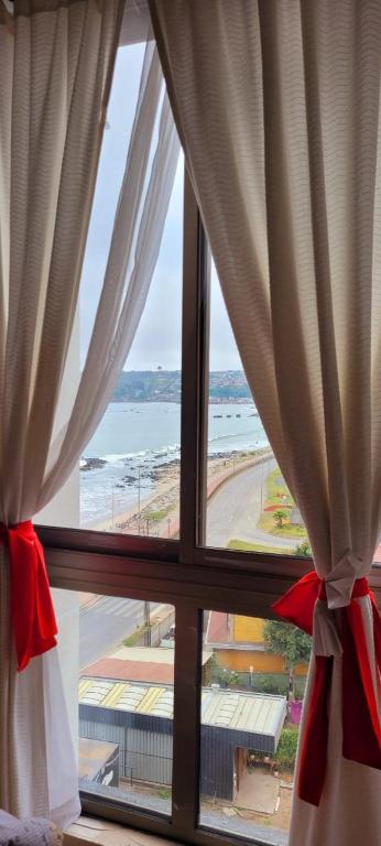 una ventana con vistas al océano desde una habitación de hotel en Playa Tomé Chile, en Tomé