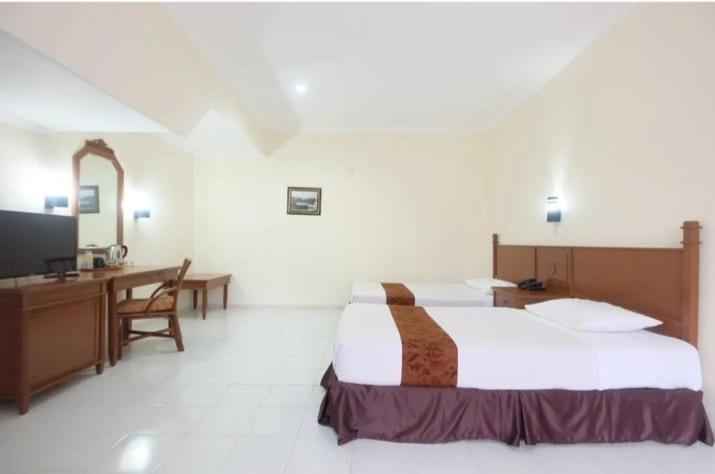 um quarto de hotel com uma cama, uma secretária e uma televisão em Griyadi Kusuma Sahid Solo em Surakarta