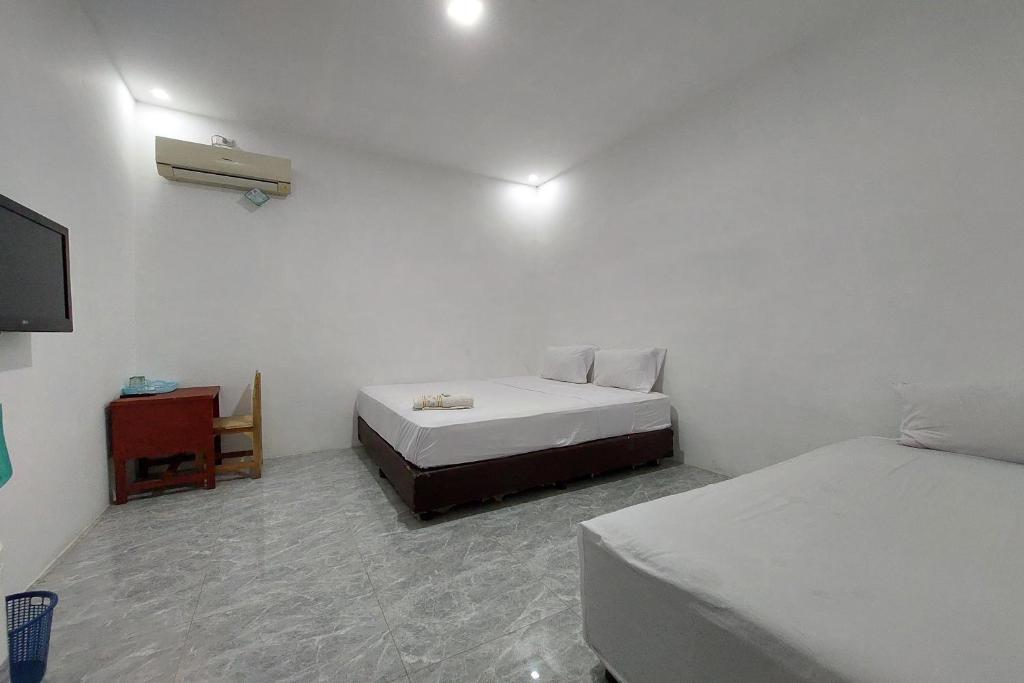 una camera con 2 letti, un tavolo e una TV di Residence Syariah a Binjai