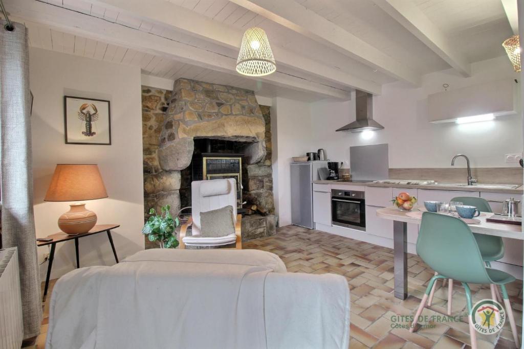 a kitchen and a living room with a stone fireplace at Kermaria in Plougrescant