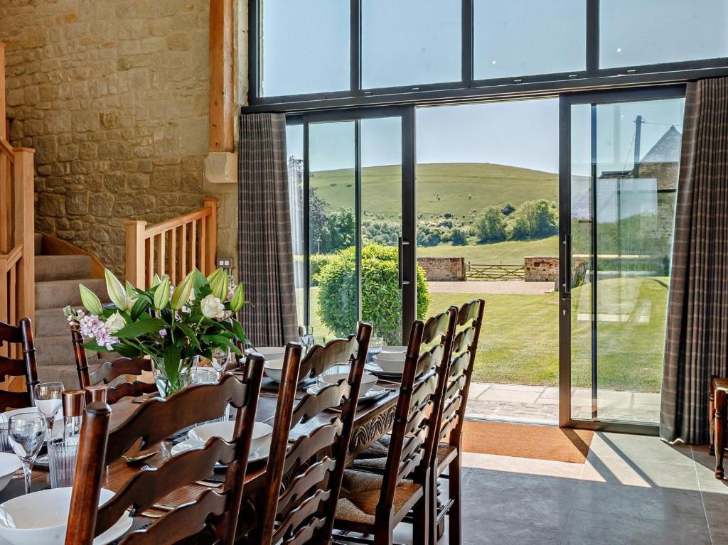 a dining room with a table with chairs and a large window at 4 Bed in Melbury Abbas 91456 in Melbury Abbas