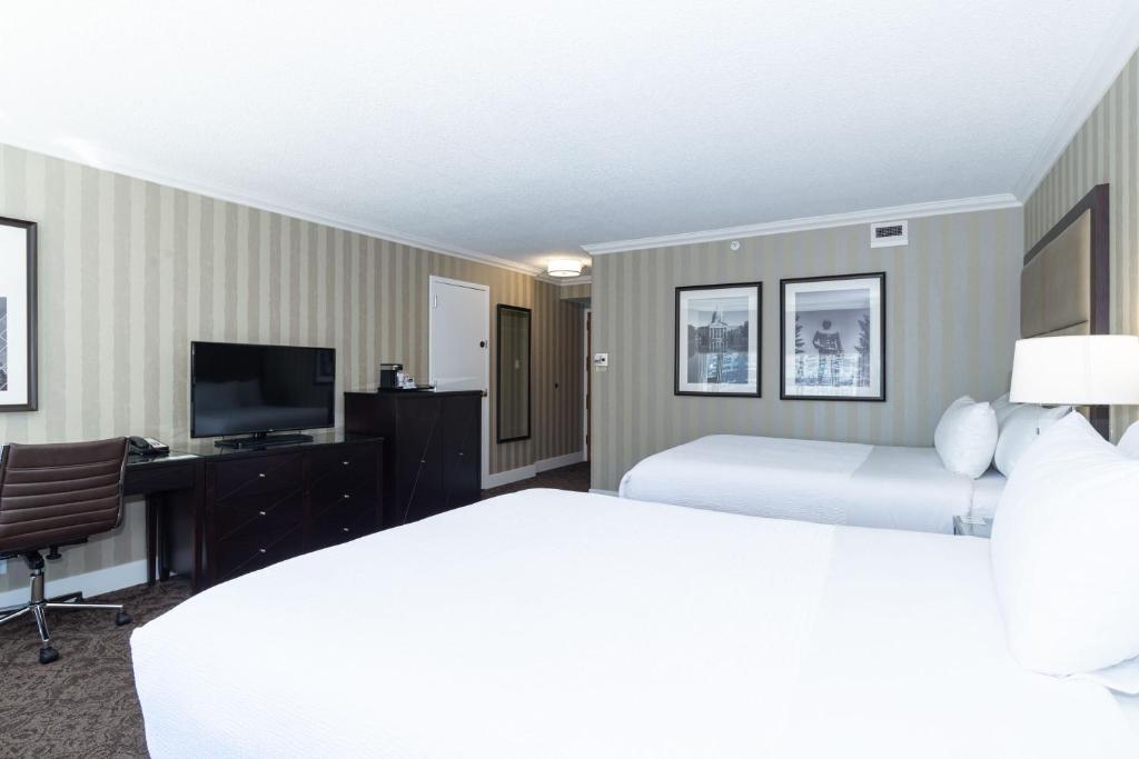 a hotel room with two beds and a television at Sandman Signature Edmonton Downtown Hotel in Edmonton