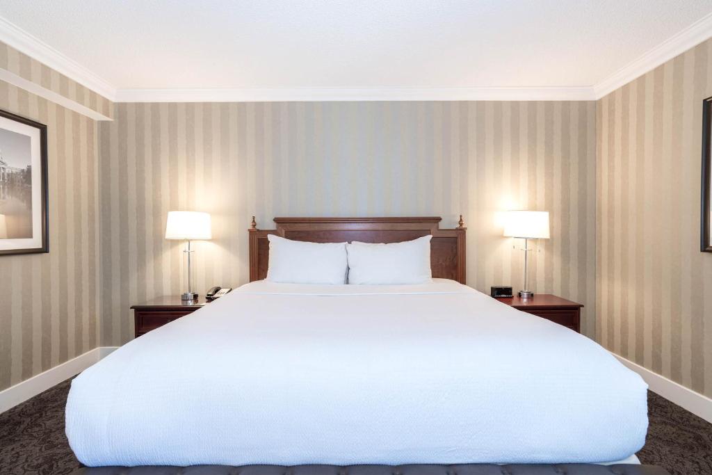 a large white bed in a room with two lamps at Sandman Signature Edmonton Downtown Hotel in Edmonton