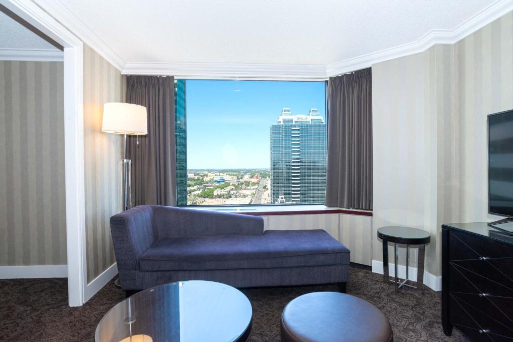 a living room with a couch and a large window at Sandman Signature Edmonton Downtown Hotel in Edmonton