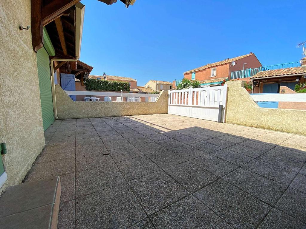 une terrasse avec une clôture blanche et une maison dans l'établissement Maison climatisée 3 pièces, 4 couchages, plage à 40m, parking, terrasse - Gruissan - FR-1-229-877, à Gruissan