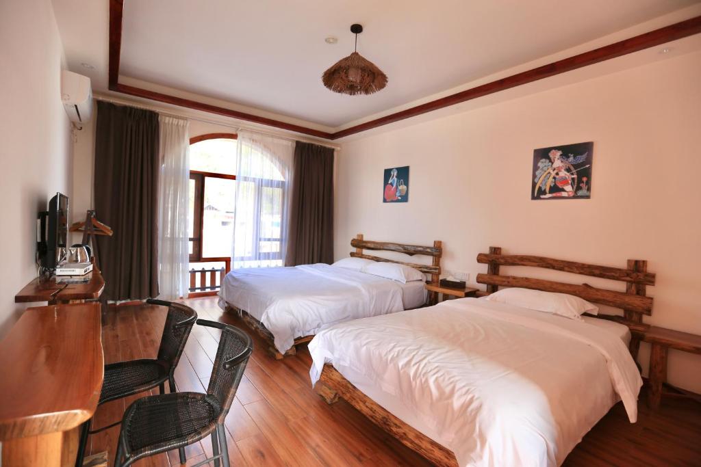 um quarto com 2 camas, uma mesa e cadeiras em Yangshuo Xiao Long River Hotel em Yangshuo