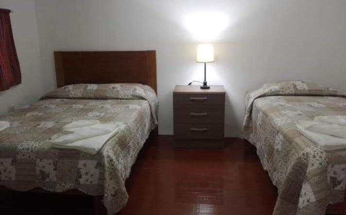 um quarto com 2 camas e um candeeiro numa mesa de cabeceira em Casa Corazao em Urubamba
