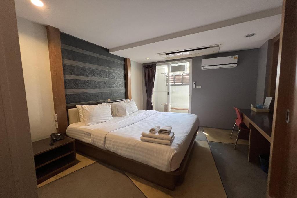 a bedroom with a bed with two towels on it at Eurna Resort Hotel in Bangkok