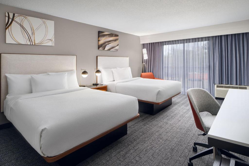 a hotel room with two beds and a desk at Courtyard Baton Rouge Siegen Lane in Baton Rouge