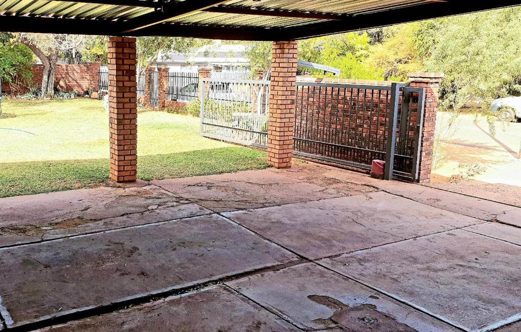 an empty patio with a gate in a yard at Rooibok 4 in Kathu