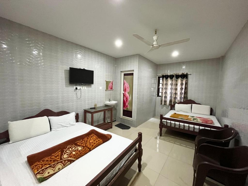 a bedroom with two beds and a flat screen tv at Sree Shanmuga Residency in Vagamon