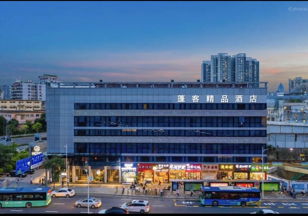 a large building with cars parked in a parking lot at Pengke Boutique Hotel - Sungang Sunway Station in Shenzhen