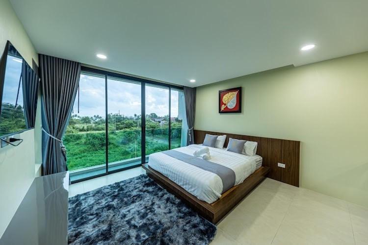 een slaapkamer met een groot bed en een groot raam bij ขนอม คิริณณ์ Khanom Kirin Private Pool Villa in Ban Plau