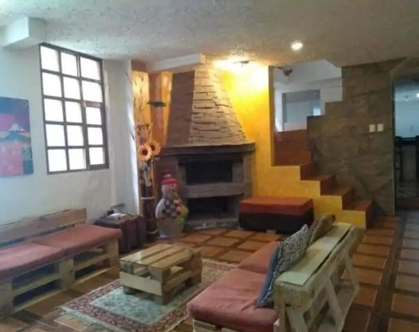 sala de estar con chimenea y escalera en La casa del Árbol, en Quito