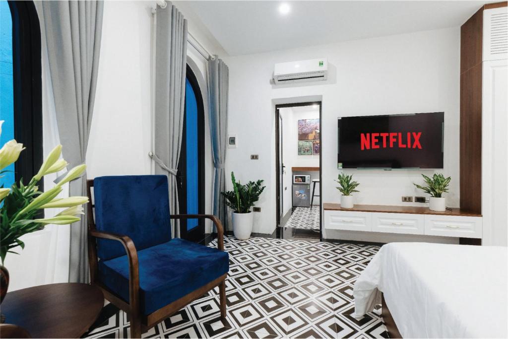 una camera d'albergo con TV e sedia blu di Hanoi Old Quarter Homestay a Hanoi
