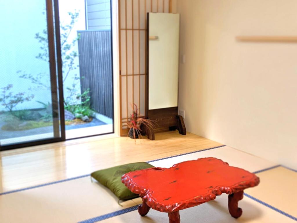 czerwony stołek w pokoju z dużym oknem w obiekcie 知輪-chirin- w mieście Sakai