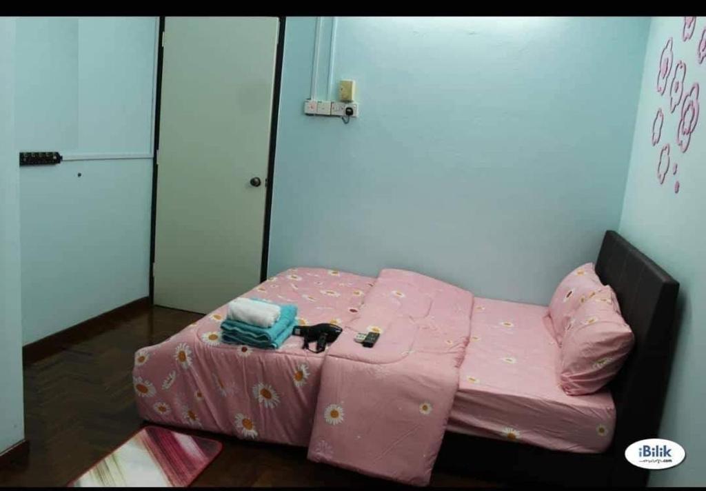 Una cama rosa con un gato sentado encima. en Rent Room, en Ipoh