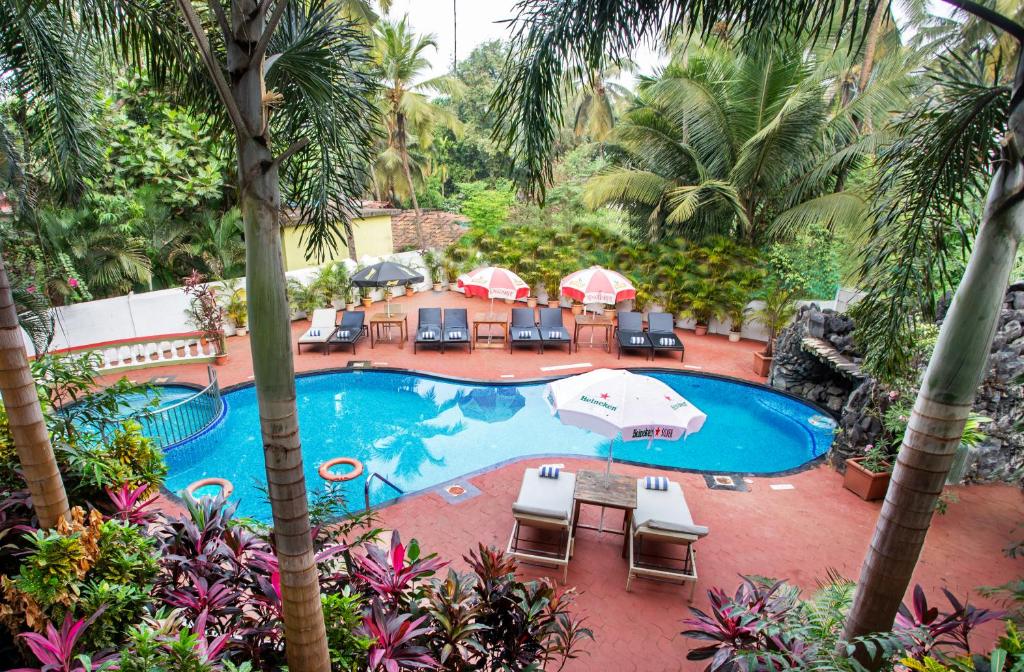 an overhead view of a swimming pool with chairs and umbrellas at Silver Sands Sunshine - Angaara in Candolim