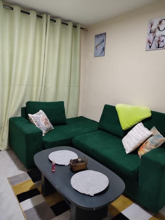 a living room with a green couch and a table at Elim apartment in Kitengela 