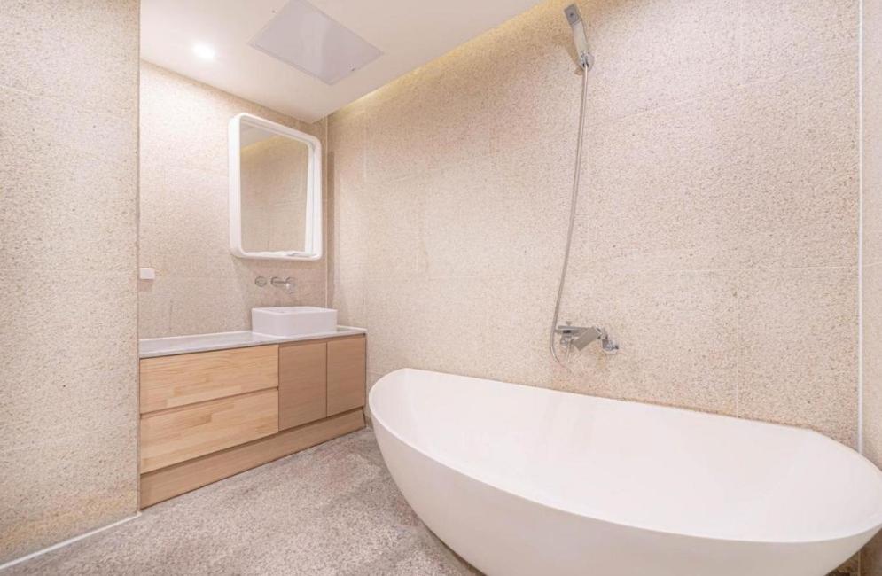 a bathroom with a white tub and a sink at H Moment Hotel Yeonsan in Busan