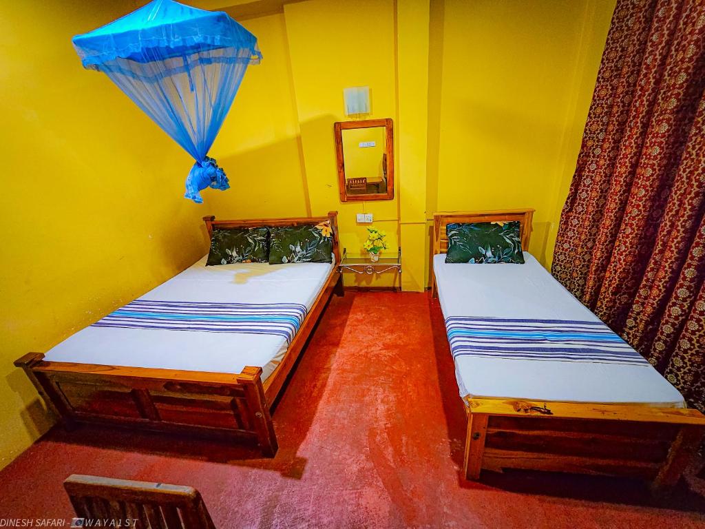 two twin beds in a room with a blue umbrella at Dinesh Safari Homestay in Udawalawe