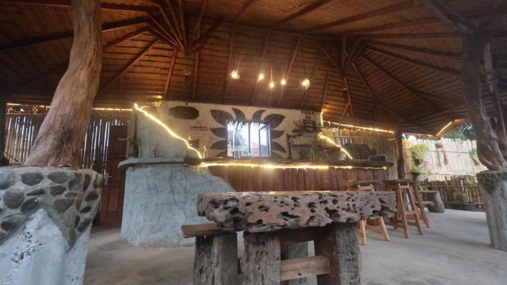 a wooden building with a table and a stone stove at eco trekking lodge Bar & tour's in Bukit Lawang