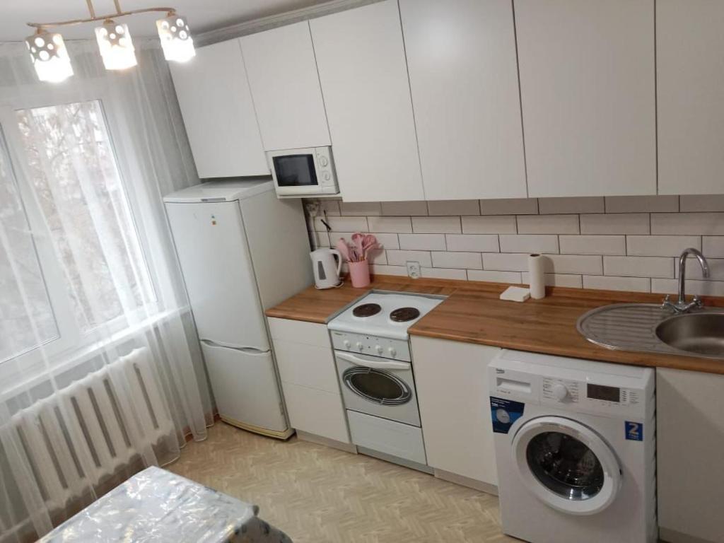 een keuken met een witte koelkast en een wasmachine bij Пермитина 1 комнатная в доль реки Иртыш in Öskemen