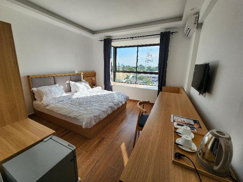 a bedroom with a bed and a table and a television at PALM VILLAGE BUSINESS HOTEL APT in Dar es Salaam