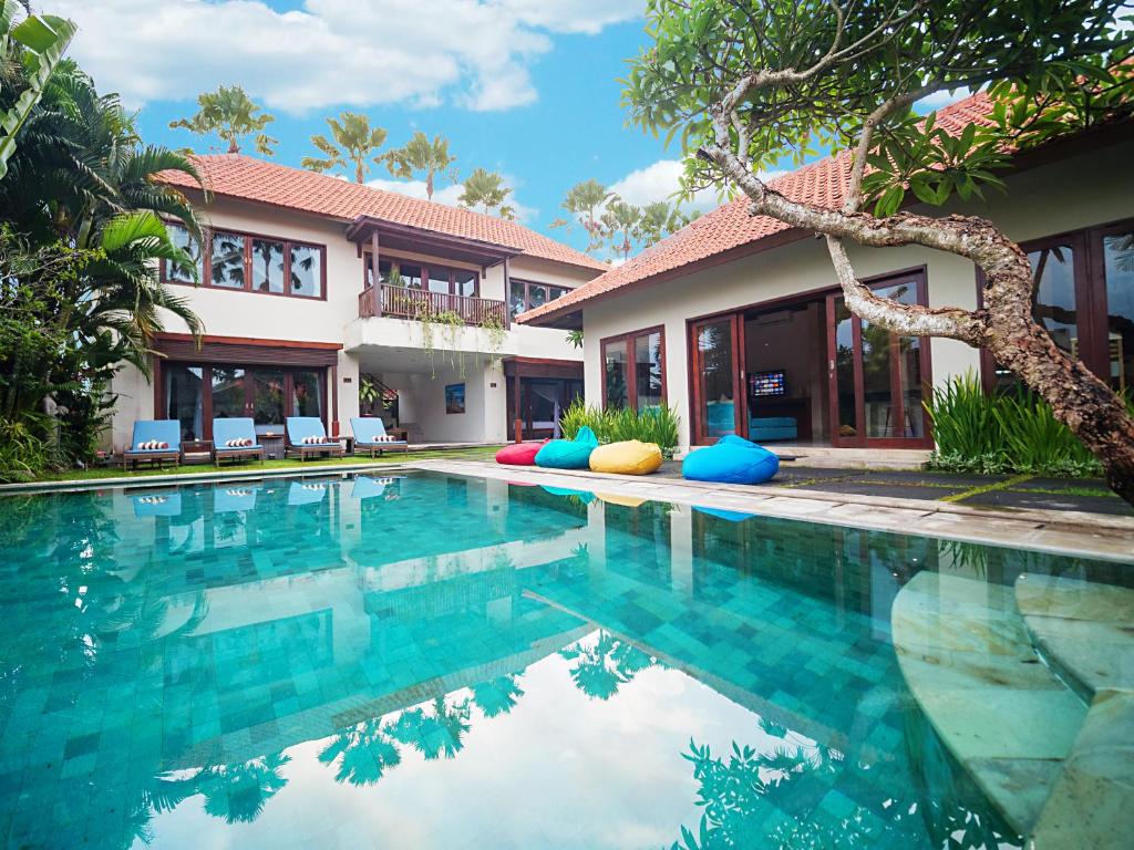 a swimming pool in front of a house at Amore Villas in Canggu