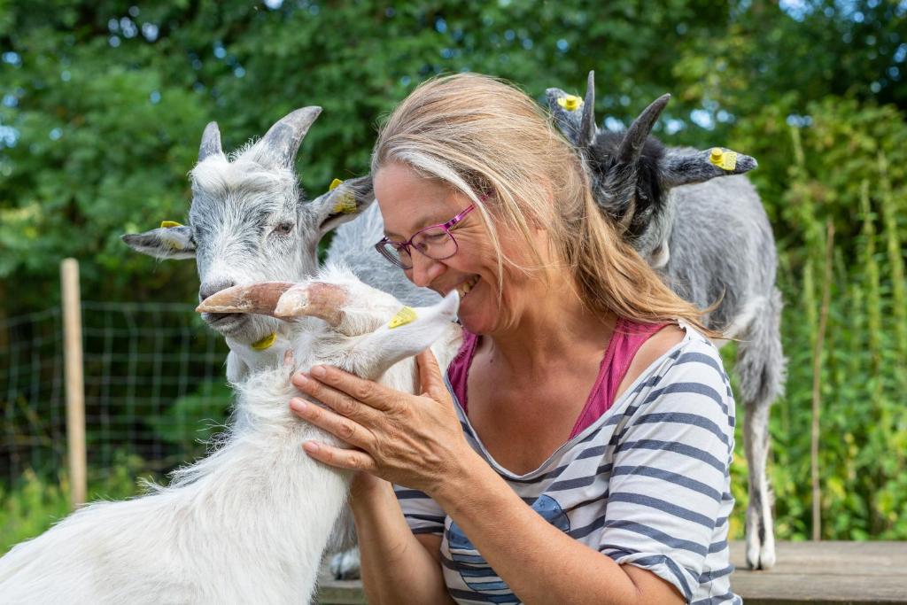 a woman is petting a goat at KirkeLy Bed and Breakfast in Vester Ulslev
