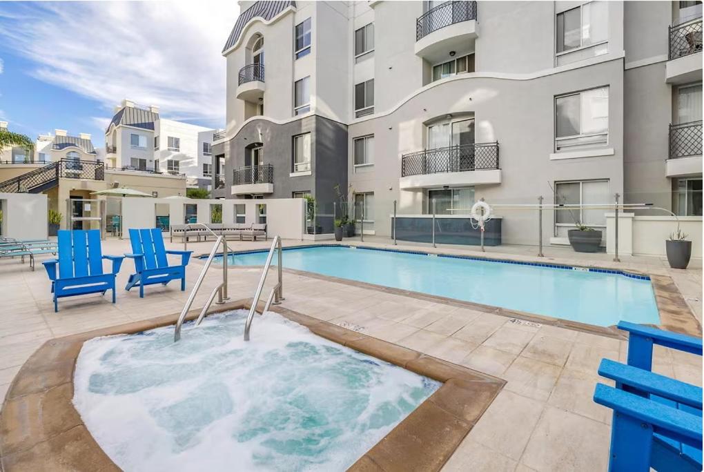 a swimming pool with blue chairs next to a building at Private Bedroom and Bathroom in Shared 2 Bedroom Apartment in Venice - Pool - Hot Tub & Gym in Los Angeles