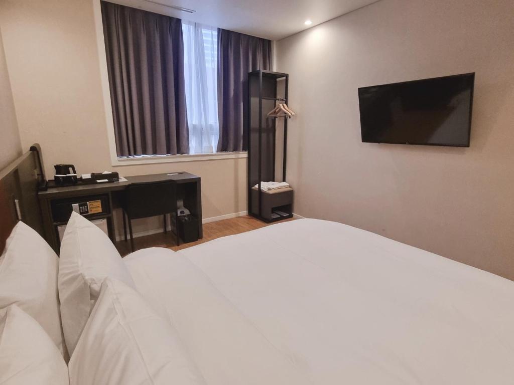 a hotel room with a bed and a television at Arban City Hotel in Busan