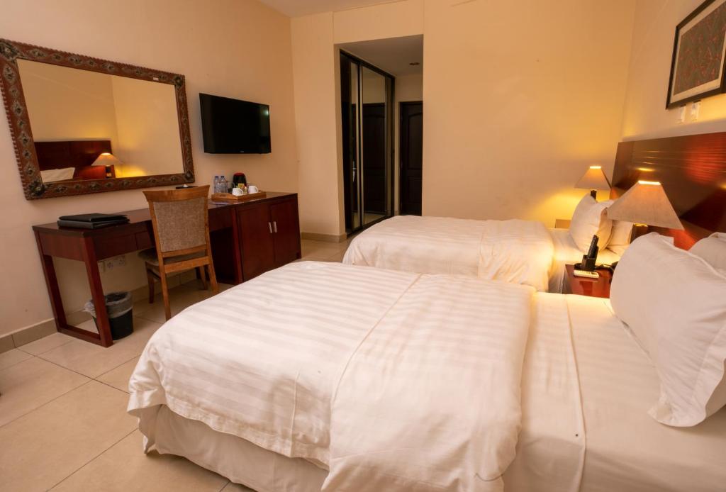 a hotel room with two beds and a mirror at La Palm Royal Beach Hotel in Accra