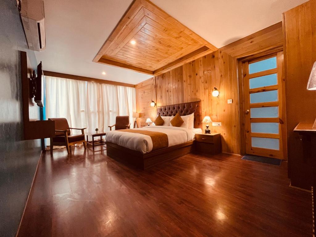 マナリにあるTATA Vista Resort Mall Road Manali - Centrally Heated & Air Cooledのベッド、テーブル、椅子が備わるホテルルームです。