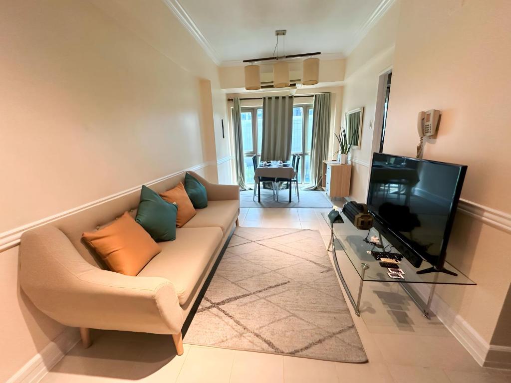 salon z kanapą i telewizorem w obiekcie Affordable Staycation Airbnb BGC w mieście Manila