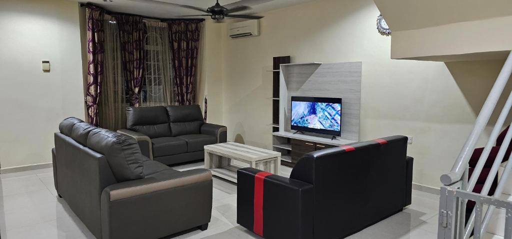 uma sala de estar com duas cadeiras e uma televisão em Kulim Square Homestay em Lunas