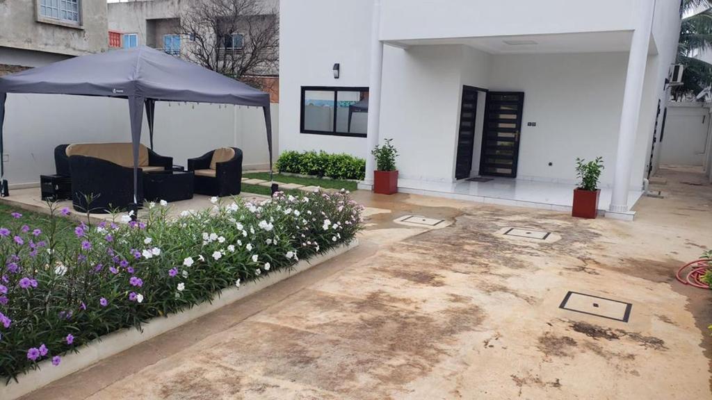 ein Haus mit einem Regenschirm und Blumen im Hof in der Unterkunft Villa luxueuse in Abomey-Calavi