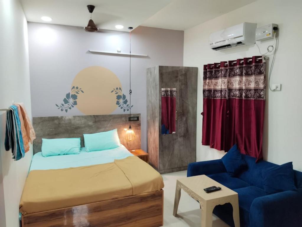 ein Schlafzimmer mit einem Bett und einem blauen Sofa in der Unterkunft ASSHAPPYSTAYINN HOTEL in Tiruchchirāppalli