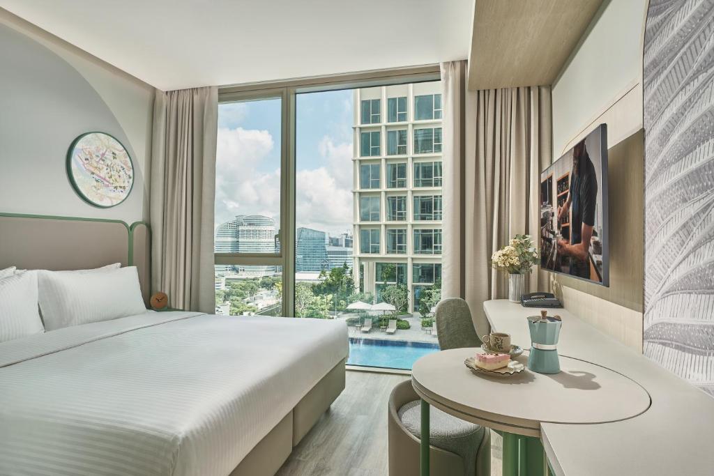 a hotel room with a large bed and a table with a table at Citadines Science Park Singapore in Singapore