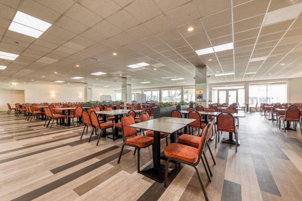a dining room with tables and chairs and windows at Corsendonk Duinse Polders in Blankenberge