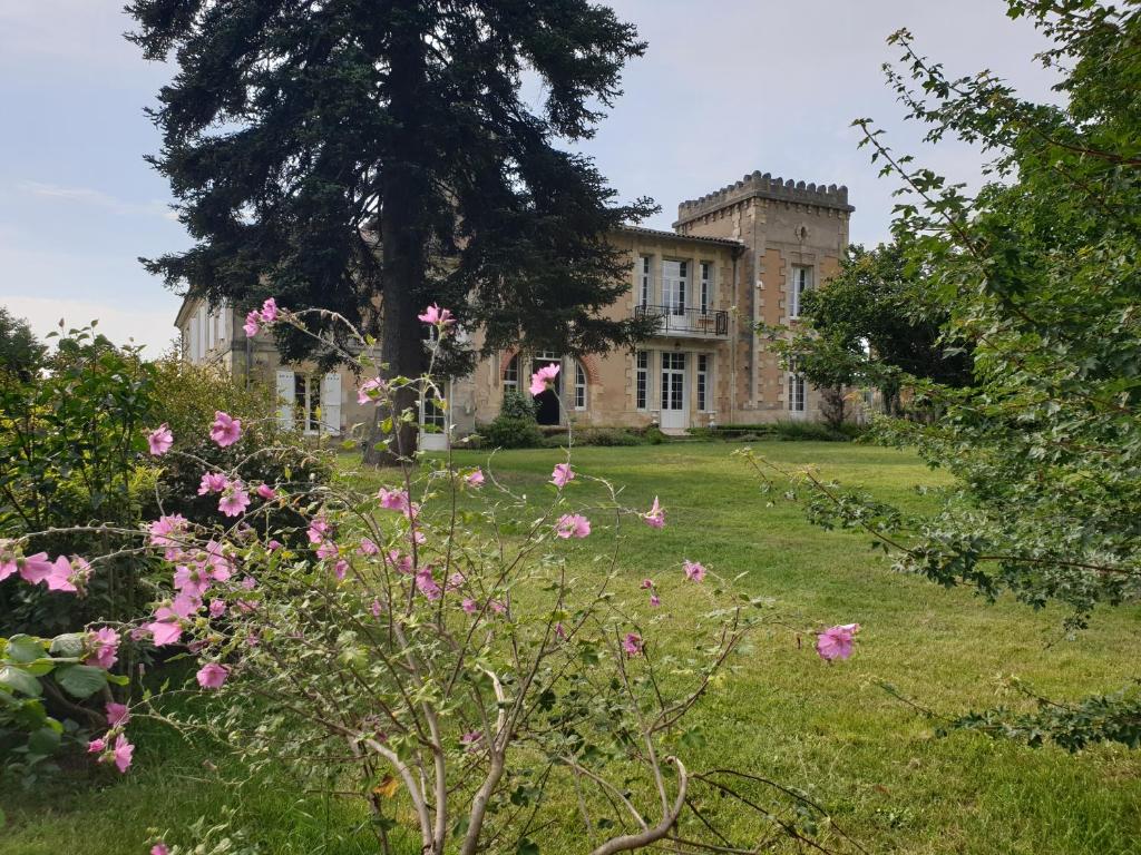 una casa vieja con flores rosas delante en Les Chambres du Séguy en Saint-Ciers-de-Canesse