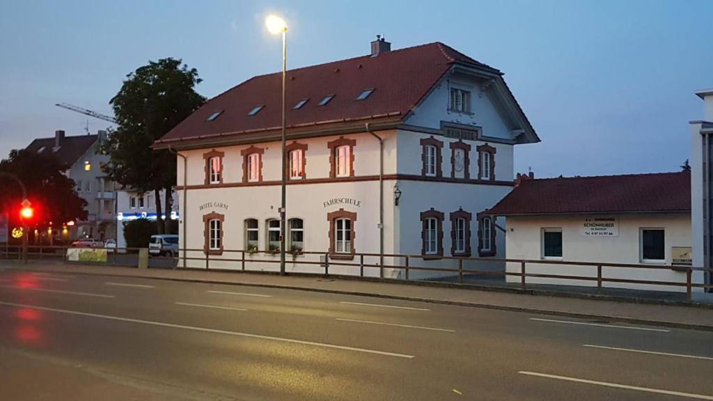 un bâtiment blanc avec un toit rouge sur le côté d'une rue dans l'établissement Pension Schönhuber, à Mainburg