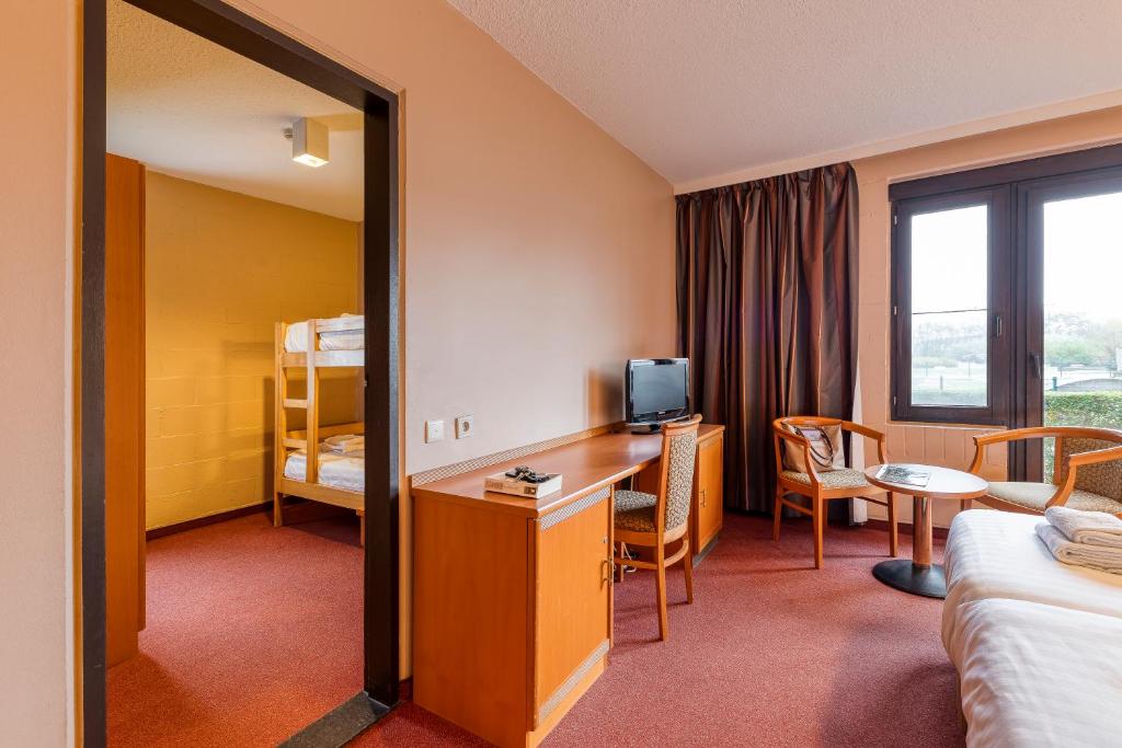 a hotel room with a desk and a bedroom at Corsendonk Duinse Polders in Blankenberge