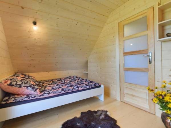 a small room with a bed in a wooden cabin at Domki Zielone Skałki in Falsztyn