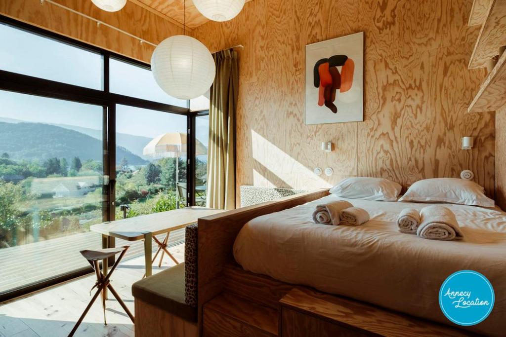 1 dormitorio con cama, escritorio y ventana grande en Ecolodge Acm Vue Lac Et Bain Nordique, en Rovagny