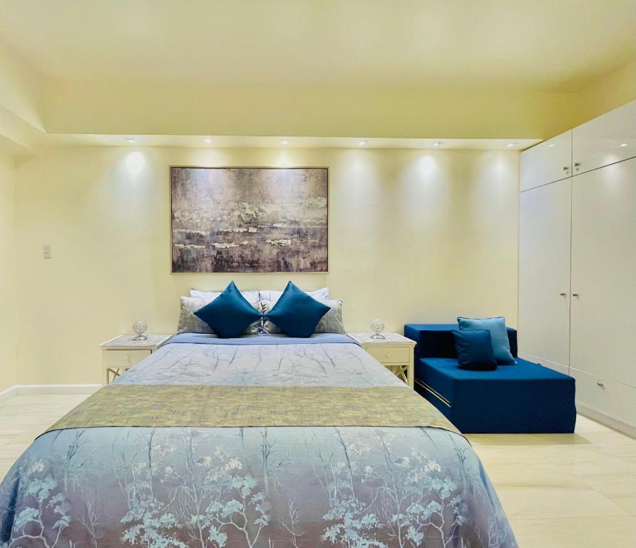 1 dormitorio con 1 cama y 2 sillas azules en Sophisticated Oceanview Studio in La Mirada, en Mactan