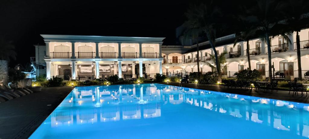 - une grande piscine en face d'un bâtiment la nuit dans l'établissement Lagoon Sarovar Premiere Resort - Pondicherry, à Pondichéry