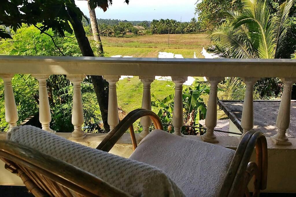 a balcony with a chair and a view of a field at 2BHK Modern Suites in North Goa in Saligao